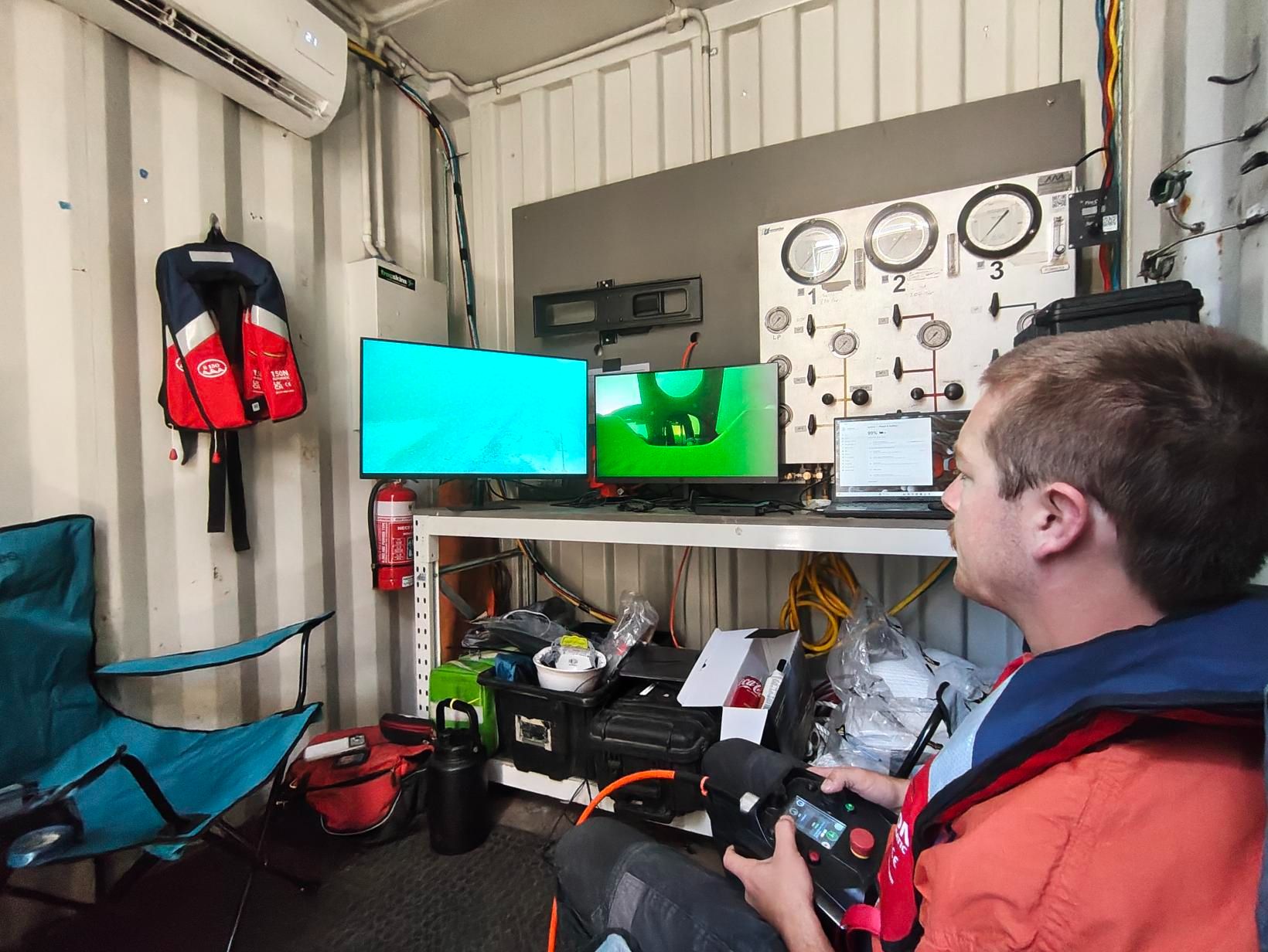 Operator monitoring live underwater feeds in a control room