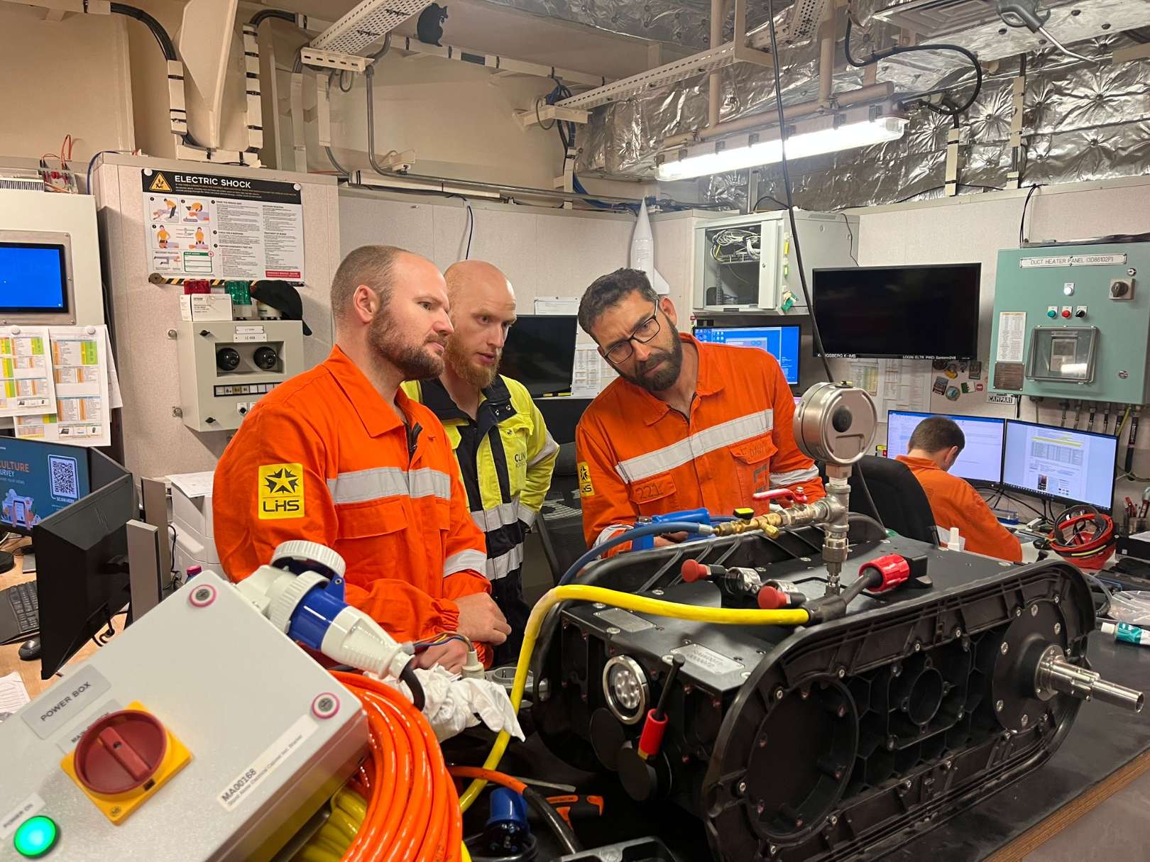 Crew inspecting a hull crawler on a workbench in a vessel workshop