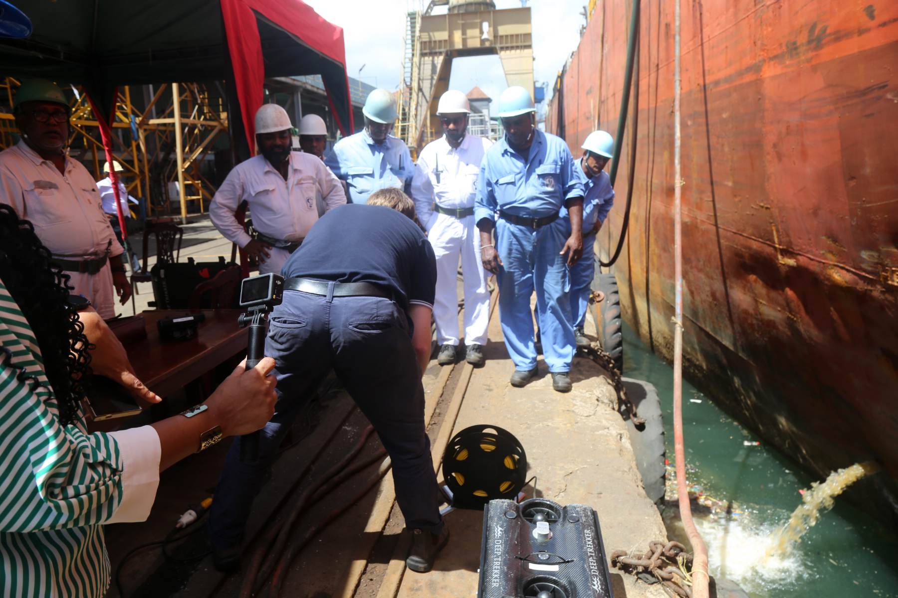 Dockside demonstration of a tracked crawler beside a vessel in dry dock