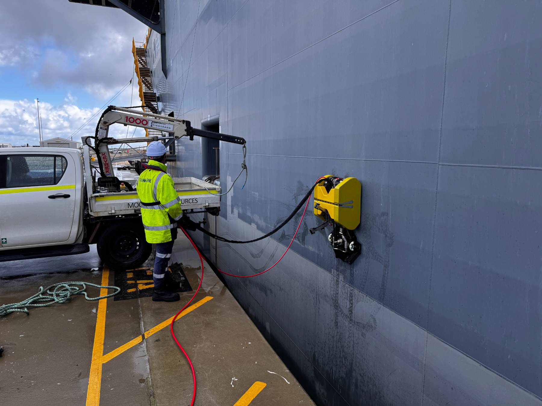 Hull crawler cleaning the side of a grey vessel