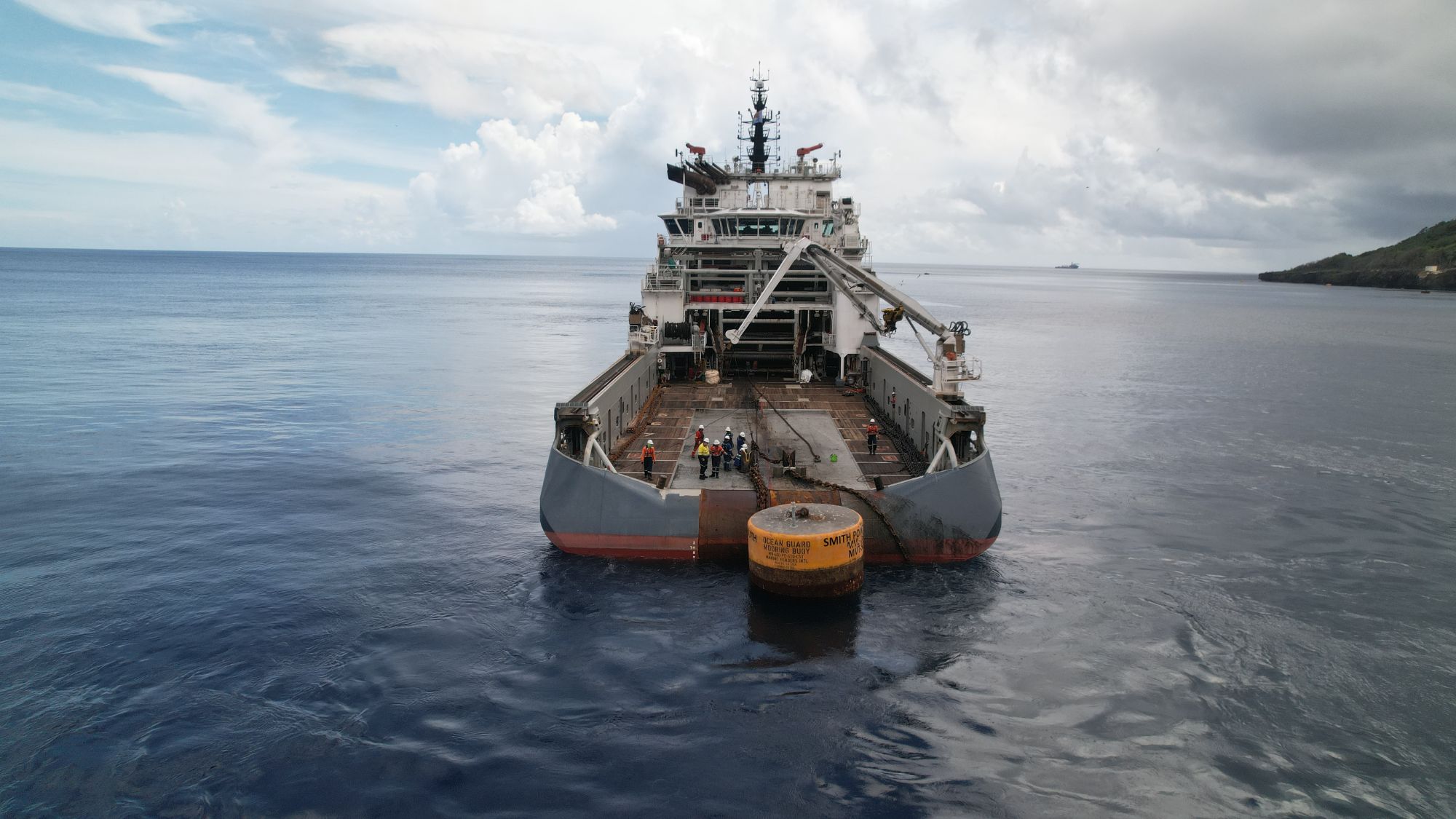 Stern of an offshore vessel with crew and a mooring buoy
