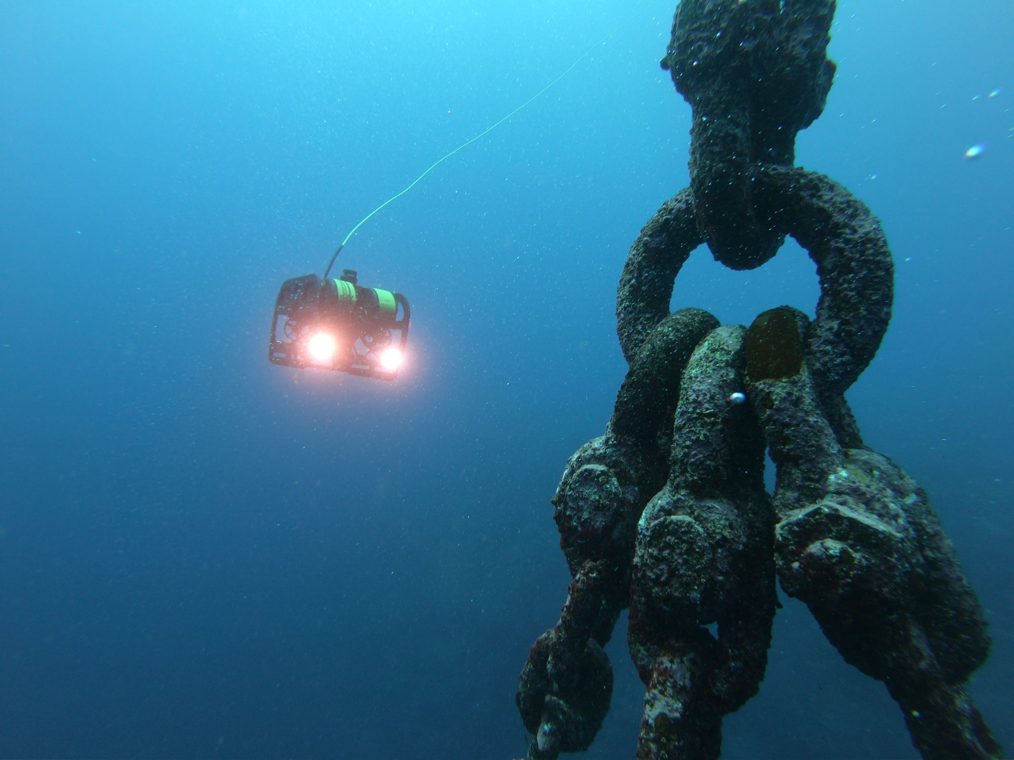 Inspection ROV with lights on approaching a fouled mooring chain