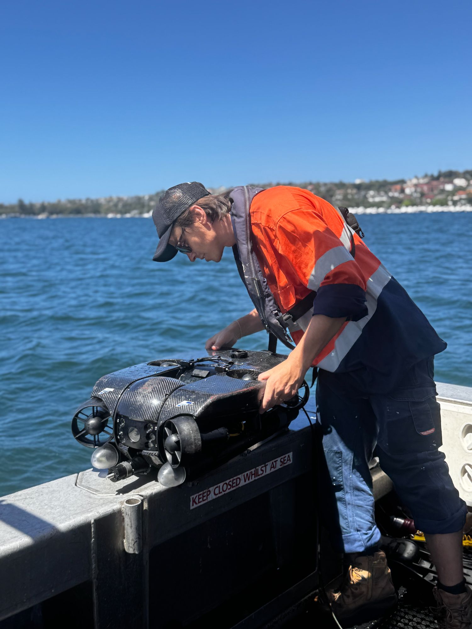 Technician launching an ROV over a vessel gunwale