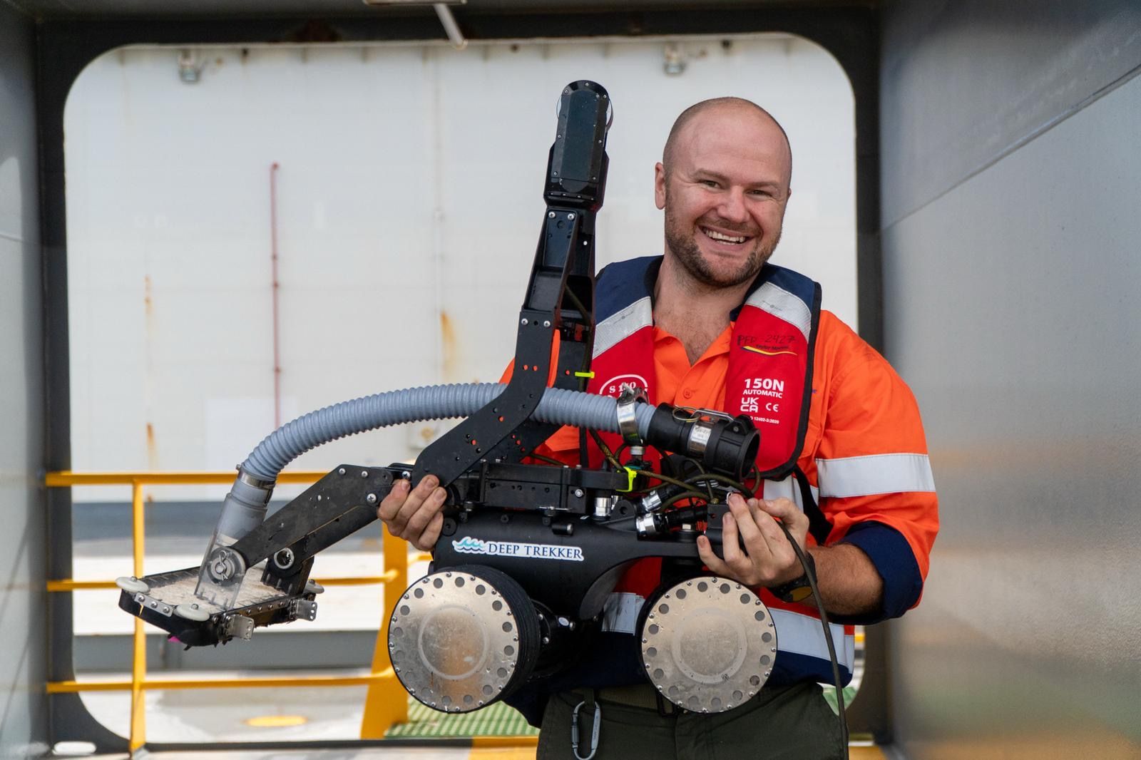 Technician holding a hull crawler in a ship's deck doorway
